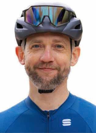Male editor in cycling helmet and blue jersey, smiling