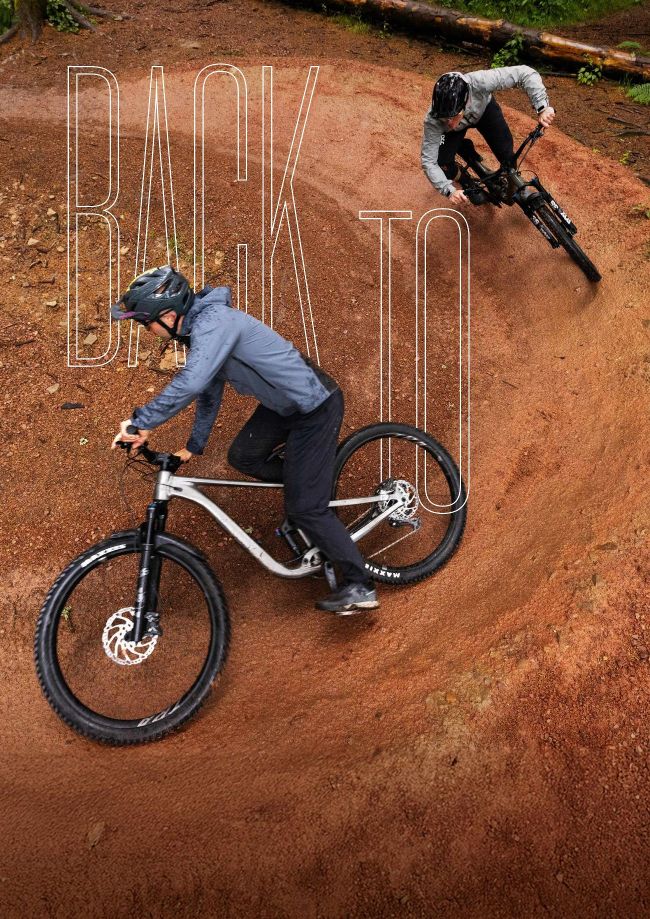 Two mountain bikers riding berms on a dirt pump track in forest