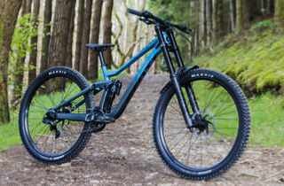 Blue full-suspension mountain bike parked on forest trail