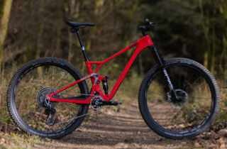 Red carbon full-suspension mountain bike on woodland path