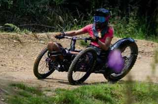 Adaptive mountain biker on three-wheeled off-road cycle on dirt track