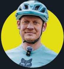 Smiling cyclist in light blue helmet and Fox jersey, yellow background