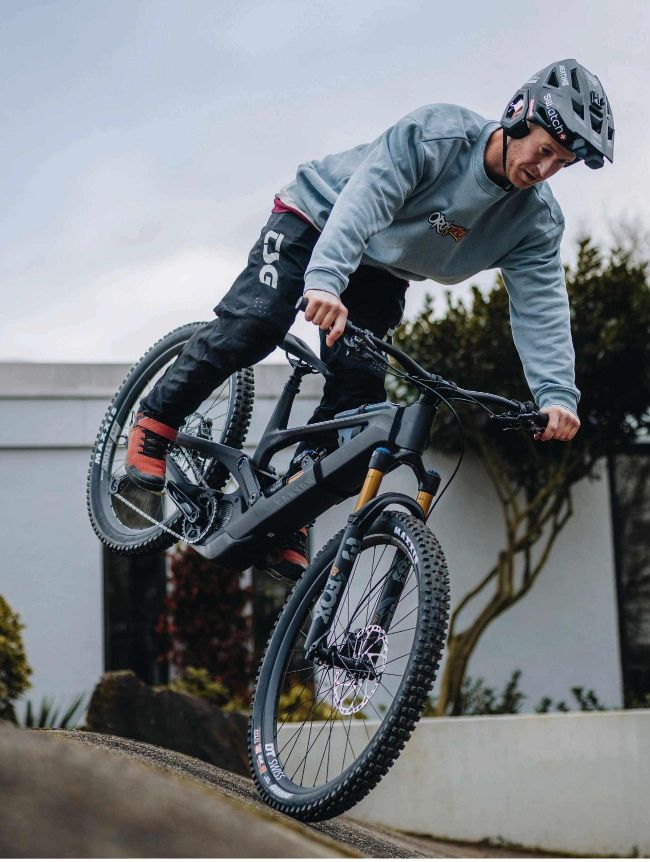 Rider performing wheelie/manual on mountain bike over urban ledge