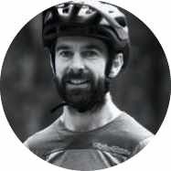Bearded male cyclist smiling, wearing black helmet, black and white