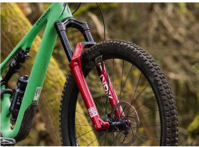 Close-up of red RockShox fork on green Specialized mountain bike