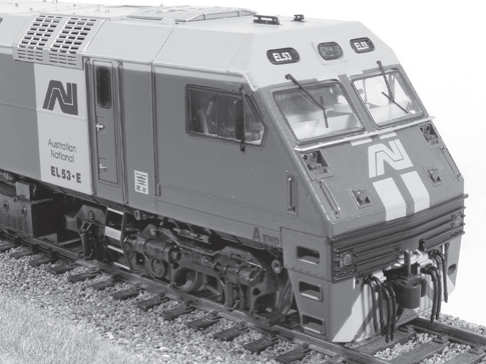 Black and white photograph of a steam locomotive, a modern electric locomotive, and a section of model railway track.